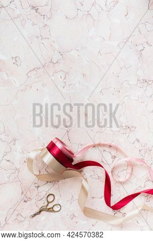 Rolls of ribbon on a pink marble background