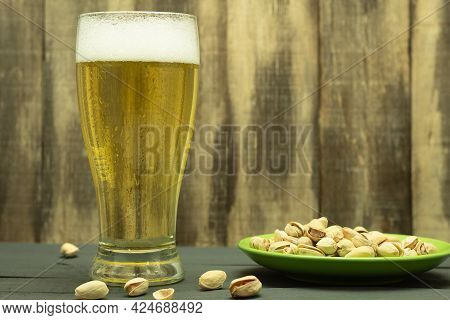 A Glass Of Cold Beer And Pistachio Nuts. A Glass Of Light Cold Frothy Beer, Nuts On An Old Wooden Ta