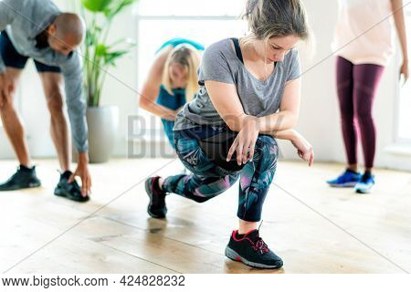 Group of people doing quadriceps stretching in class