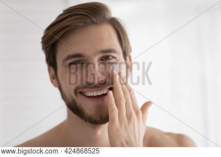 Head Shot Of Young Attractive Guy Applying Moisturizer