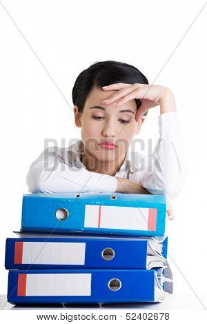 Sad woman with ringbinders sitting at the desk. Tired and exhousted business woman.