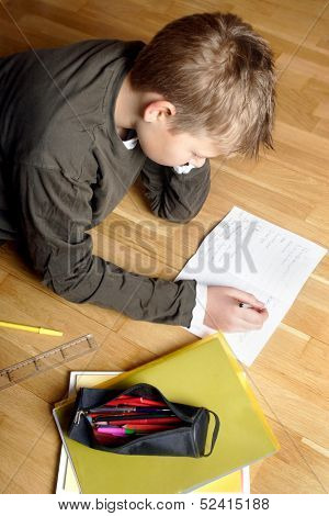 boy writing on paper, lying on the ground