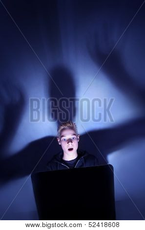 12 year old boy illuminated by the blue light of a computer monitor
