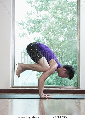 Man with legs off the ground and balancing in yoga position 