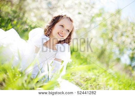 The beautiful little girl, with bush blossoming apple-tree, smil