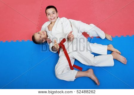 Two young athlete with a red and white belt show finger super