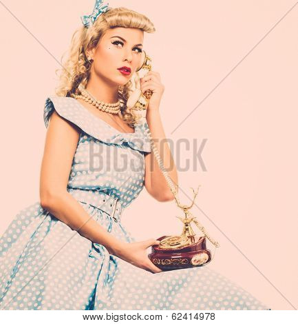 Coquette blond pin up style young woman in blue dress with vintage phone 
