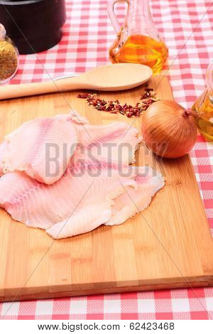 Raw fish tilapia on cutting board and spices