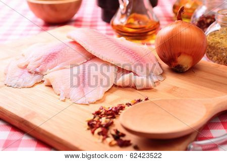 Raw fish tilapia on cutting board and spices