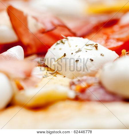 Raw pizza dough with mozzarella and proscuitto on top