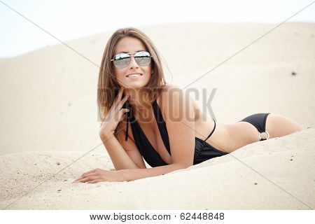 A beautifull caucasian girl lying on the sand,
