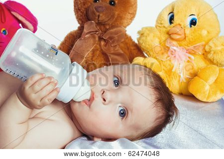 Baby with blue eyes drinking from a bottle
