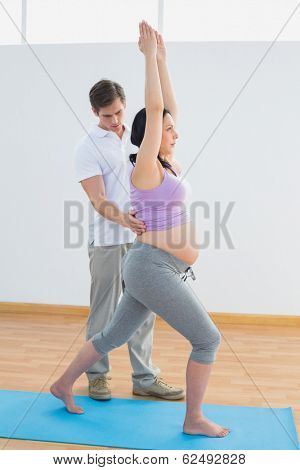 Pregnant woman doing yoga with a personal trainer in a fitness studio