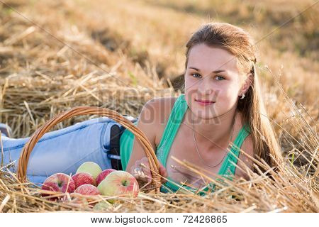 Teen girl with  basket of apples in the field