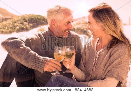 Couple enjoying white wine on picnic at the beach on a bright but cool day