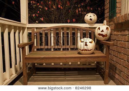 weiße Jack o'lanterns auf einer Bank