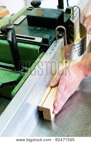 Carpenter working on an electric buzz saw or wood milling and cutting some boards in carpentry