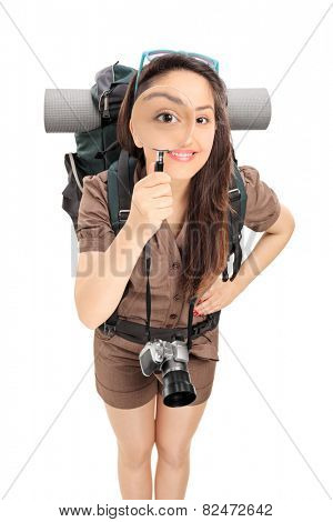 Female tourist looking through a magnifying glass isolated on white background