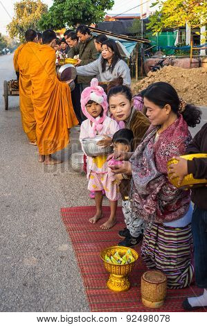 locals give food offerings to Buddhist monks