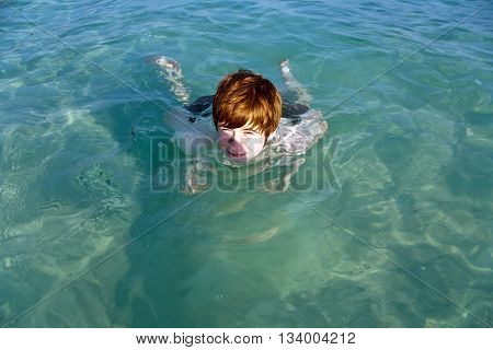 boy enjoys swimming in the blue ocean