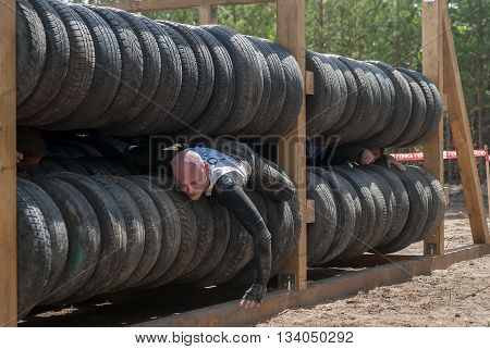 Tyumen Russia - June 11 2016: Race of Heroes project on the ground of the highest military and engineering school. Athlete moves between old tires. Human birth stage