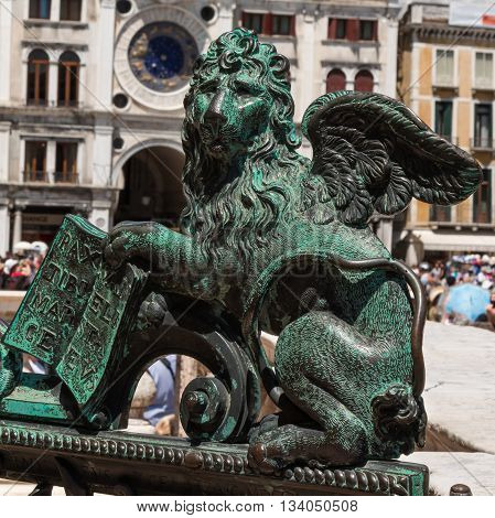 Bronze Winged Lion Statue and Torre dell'Orologio building in background in St. Mark's Square Venice Italy