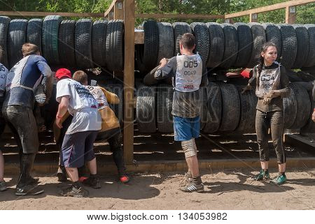 Tyumen Russia - June 11 2016: Race of Heroes project on the ground of the highest military and engineering school. Sportsmen move between old tires. Human birth stage