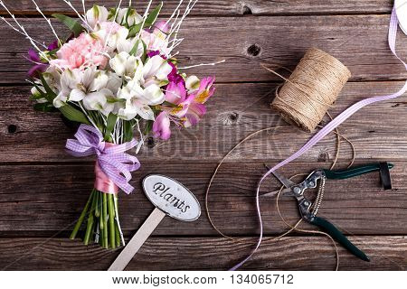 Rustic bouquet from gillyflowers and white alstroemeria on old rustic wooden background with wooden heart and scissors