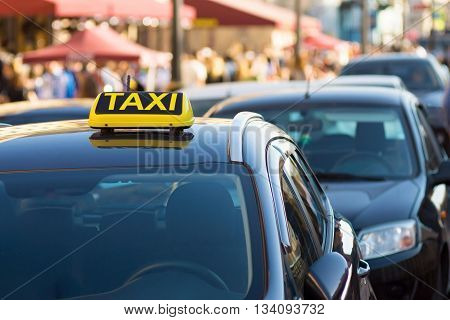 symbol or sign with an inscription of a taxi is located on a car roof on an indistinct background city street and blank space