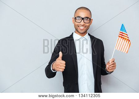 Happy african man holding national flag of United states of America and showing thumbs up