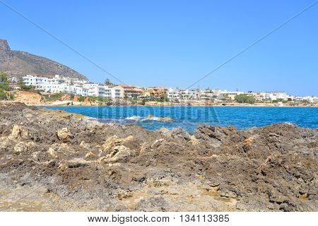 Rocks on the shore of the sea and the city of Hersonissos Crete Greece.