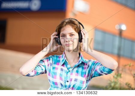 Young beautiful girl listening to music player on the street. tudent woman at campus park.
