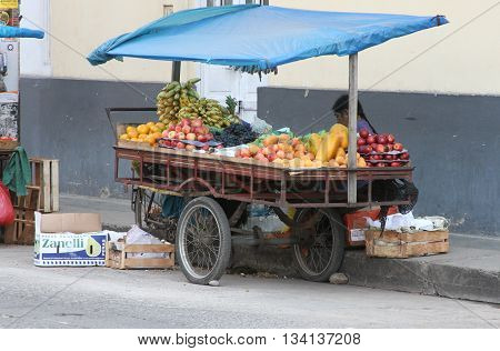 Cajamarca Peru - June 11 2016: Andean woman sells fruit from fruit cart in Cajamarca Peru on June 11 2016