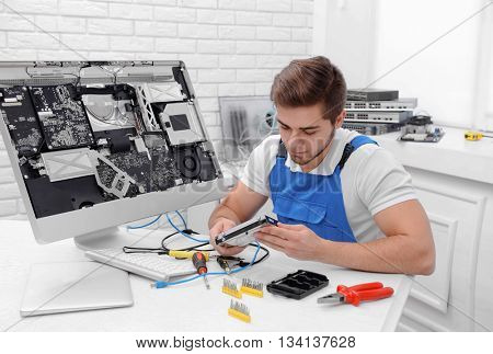 Young repairer disassembling a computer internal parts in service center
