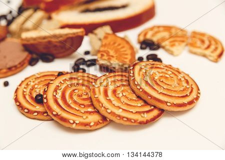 There are Pieces of  Roll with poppyseed,Cookies,Halavah,Chocolate Peas,Tasty Sweet Food on the White Background.Toned