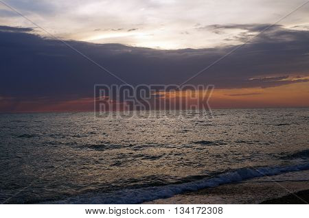 Orange sunset with dark blue- purple clouds over the Black Sea in the summer evening