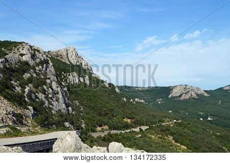 High mountains covered with green forests on the background of blue sky along the road in Crimea