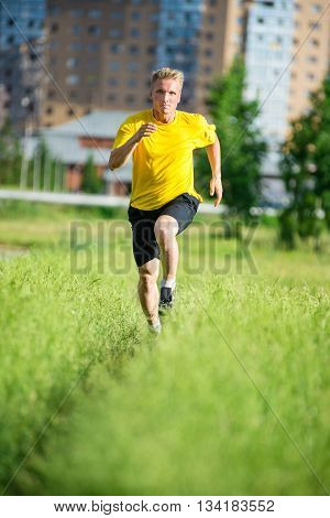 Running man jogging in city street park at beautiful summer day. Sport fitness model caucasian ethnicity training outdoor.