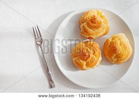 Profiteroles, choux with a custard cream, creme anglaise, whipped cream, dessert on a white plate Copy space Top view