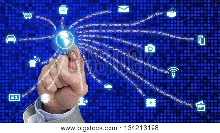 Finger presses glowing globe connecting internet of things icons with digital datastreams on blue dotted background