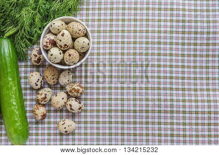 Quail eggs in a white bowl and a scattering of eggs and fresh herbs on a light background