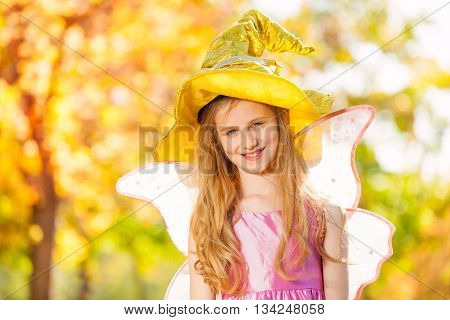 Girl in costume of fairy standing alone in the forest during sunny autumn day time
