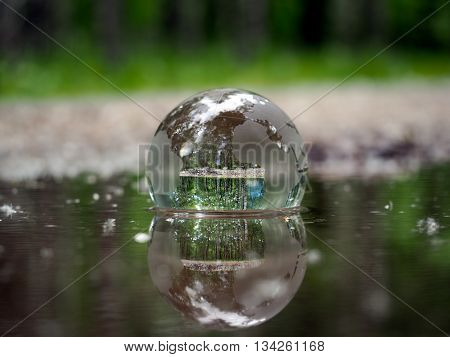 Transparent ball in the water on a forest background. The concept - ecology, environment, water Ballance