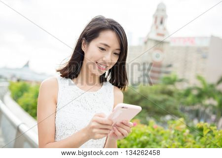 Woman use of mobile phone with hong kong clock tower
