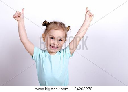 little girl in a blue t-shirt raised her hands up and smiling blonde