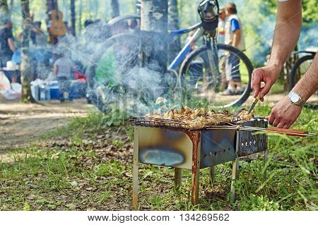 People preparing a shashlik on the braizer on the outdoor party