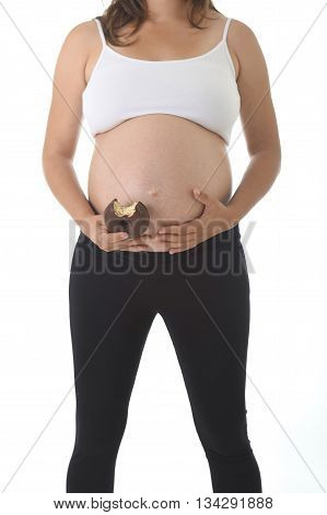 young pregnant woman holding her big belly with hand and eating chocolate donut happy isolated on white background in pregnancy whim food concept isolated on white background