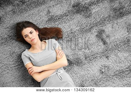 Beautiful girl lying on grey floor