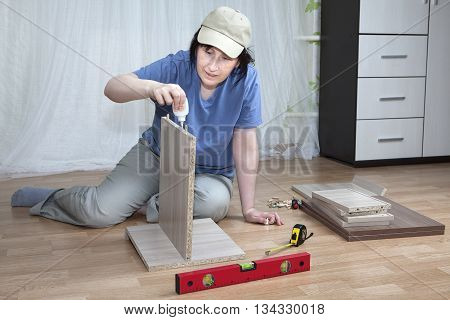 Woman putting together self assembly furniture assemble flat pack.