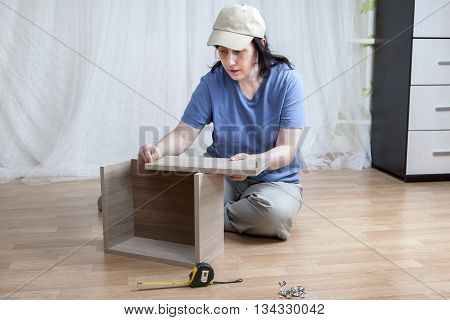 One Caucasian woman self assembly new furniture sitting on the floor.